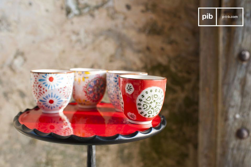 Vier grifflose Keramikbecher mit Blumenmotiven.