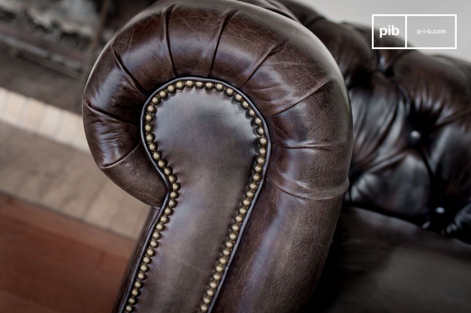 Die Armlehnen dieses Sofas sind mit einer genagelten Ledergarnitur gepolstert.